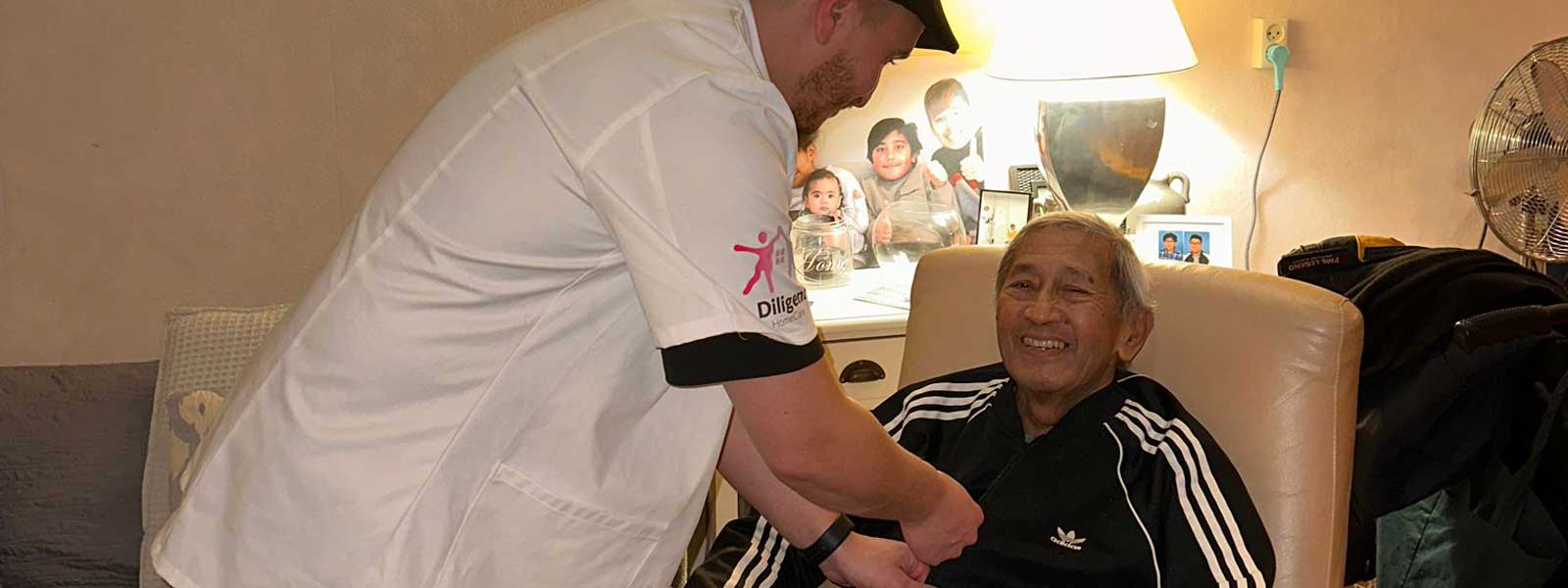 Verpleger helpt oudere man met het aantrekken van kleding